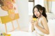 A woman sitting at a table holding a cup of orange juice.