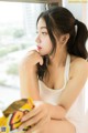 A woman sitting on a window sill holding a bag of chips.